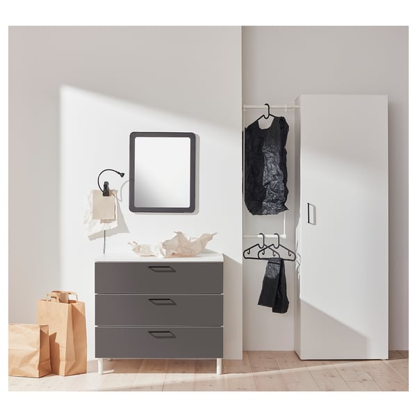 Modern minimalist bedroom: grey PLATSA dresser with mirror, hanging clothes, wooden floor, white wardrobe.