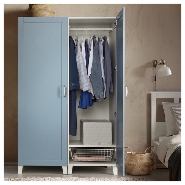 Blue PLATSA wardrobe with clothes and storage bins in a bedroom.