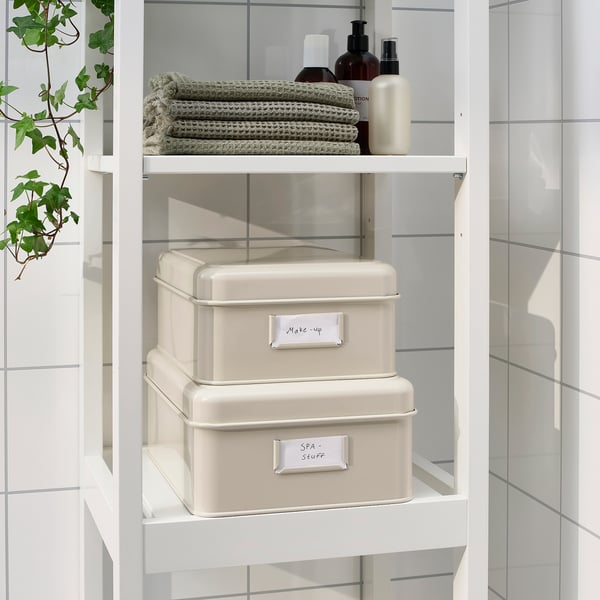 White metal storage boxes with labels make-up and spa-scents on shelves in bathroom.