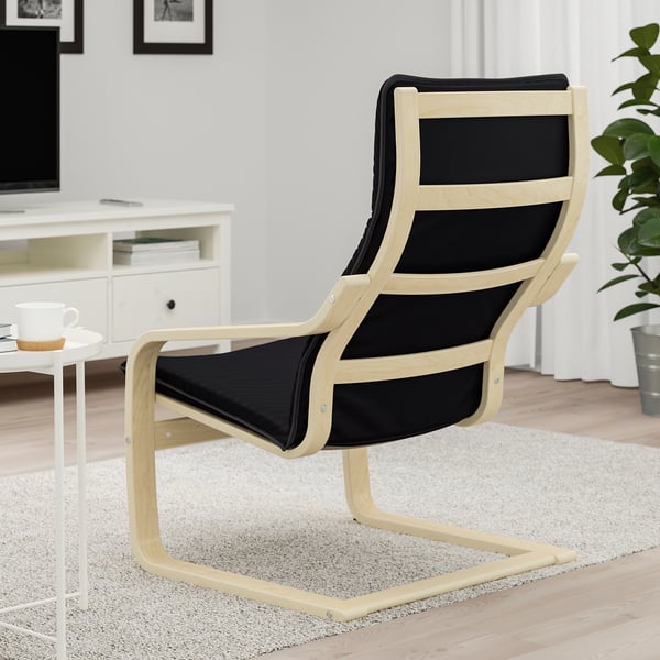 Black cushioned wooden chair, reclined, near a small white table with a mug and coaster.