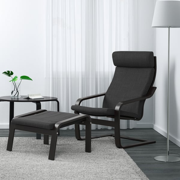 Modern chair & ottoman, dark grey, high back. Beside light rug, white curtains.