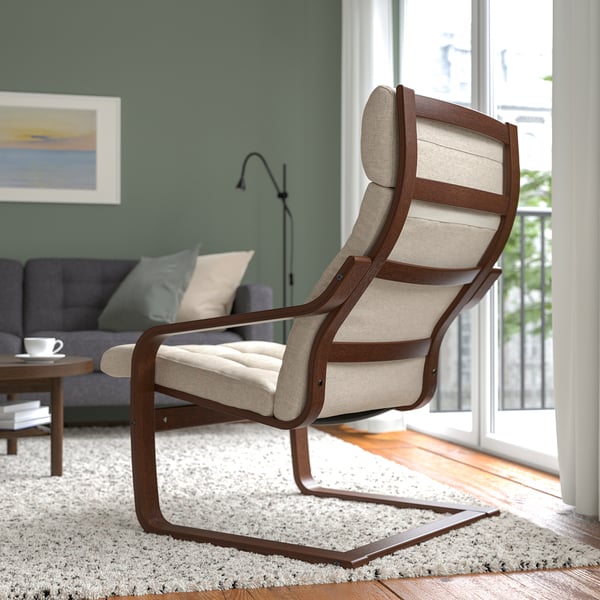 Beige fabric POÄNG armchair offers neck support & resilience, placed near a window.
