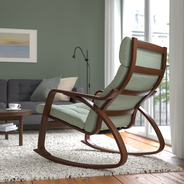 A modern rocking chair with curved wooden lines and a cushioned seat is placed near a window, offering relaxation and comfort.