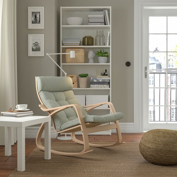 POÄNG rocking chair, light hue, beside window, cosy cushioned seat.