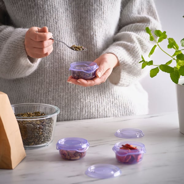 Person holding seed container, demonstrating food storage with organised containers and seeds.
