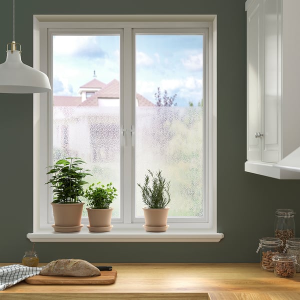 Kitchen with green walls, large window, plants, snacks, bread, houses view.