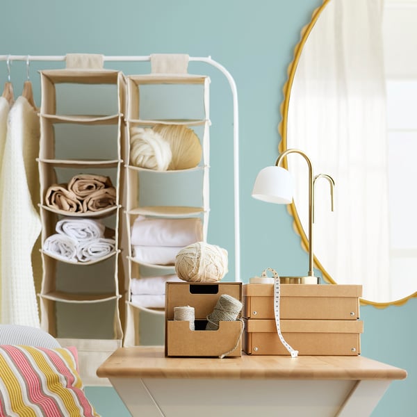 Organised craft room with shelves holding yarn, fabric, and a desk lamp.