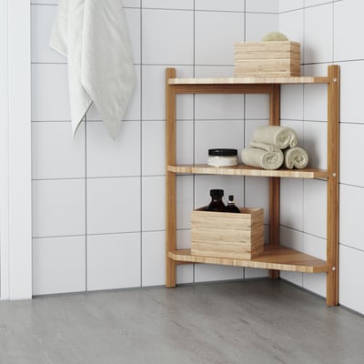 Corner bamboo shelf with towels & boxes in white-tiled bathroom.