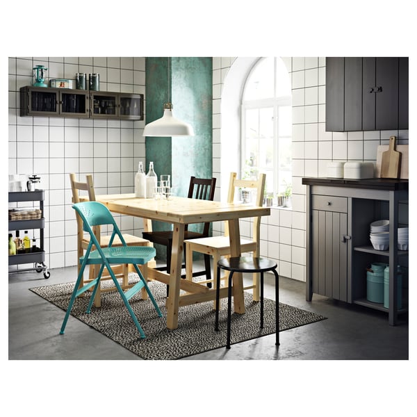 Modern kitchen with natural wood table, teal chairs, white pendant lamp, grey cabinets, and steel accents.