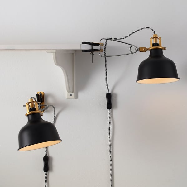 Two adjustable wall lamps: one clamped, one mounted, with black shades and brass accents.