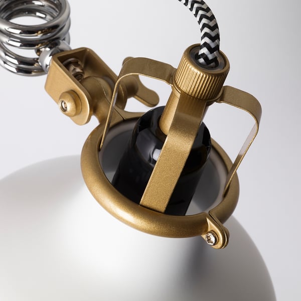 Gold-coloured metal clamp lamp with black shade, detailed joints, sturdy design.