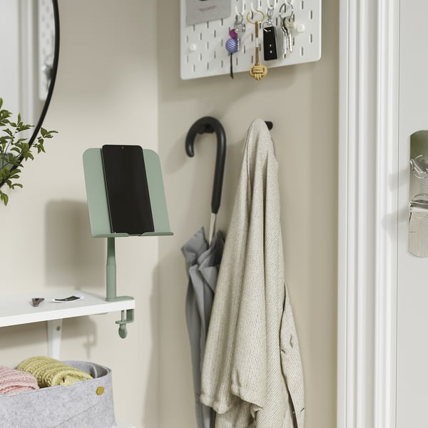 Entryway with light blue tablet holder for hands-free use, white shelf, coat hook with beige coat, keys, and a plant.