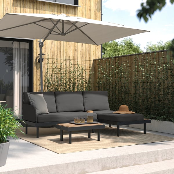 Modern backyard patio with black outdoor sectional, coffee table, and large umbrella for shade.