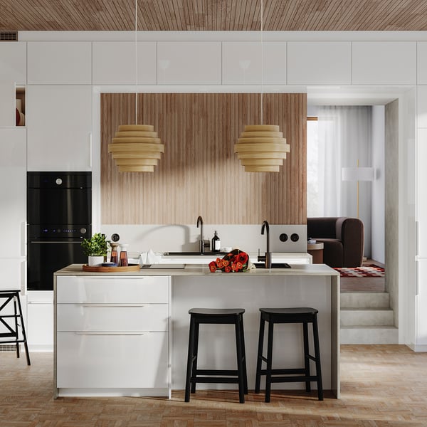 Modern kitchen with white high-gloss cabinets, wooden accents, black stools, and unique pendant lights.