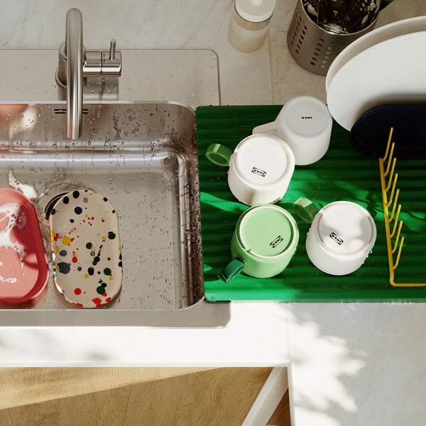Stainless sink with tap, water droplets, dish drainer, and containers.