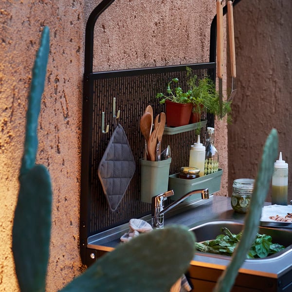 Kitchen rack with hooks and items for cooking. Stainless steel sink with food prep area.