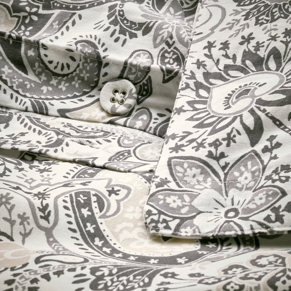 Close-up of decorative button on paisley-patterned duvet cover with envelope closure.