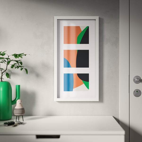 Abstract art in white room. Three colourful prints, left plant.