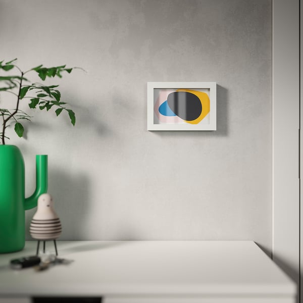 Minimalist room with green vase, white lamp, and colourful wall art.