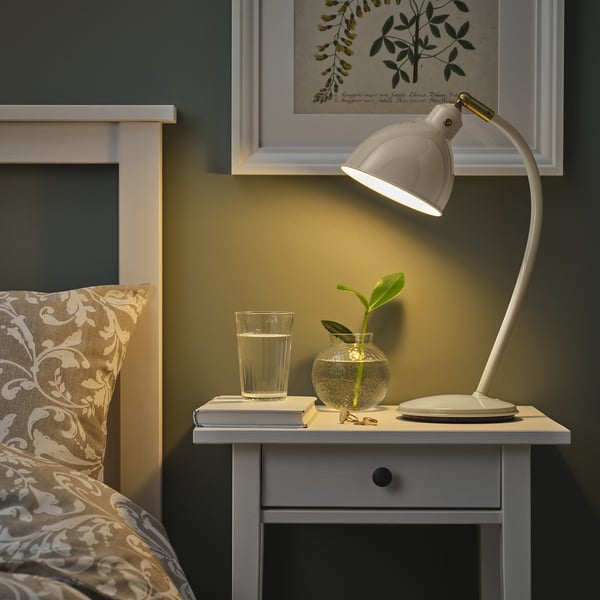 Cosy bedroom with RÖDFLIK lamp, bedside table, plant, and wall picture.