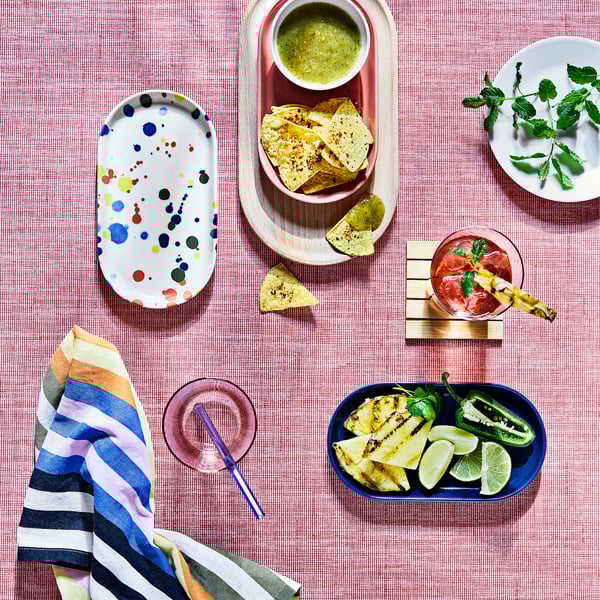 Colourful IKEA RÖDSNULTRA plates with patterns set on a table with snacks and drinks.
