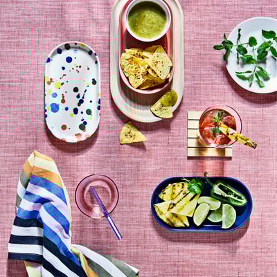 Colourful IKEA RÖDSNULTRA plates with patterns set on a table with snacks and drinks.