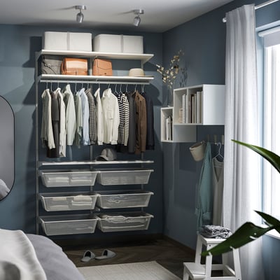 Modern closet with blue walls, spotlight, neat clothes, shelves, and mirror.