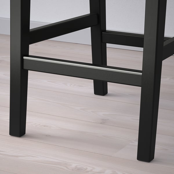 Black wooden bar stool with sturdy legs and footrest on light wooden floor.