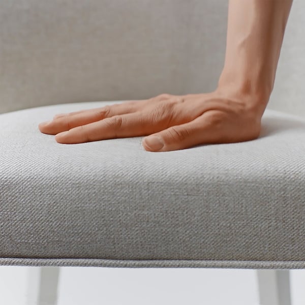 Hand rests on soft, upholstered seat of modern chair, showcasing comfort and high-quality fabric.