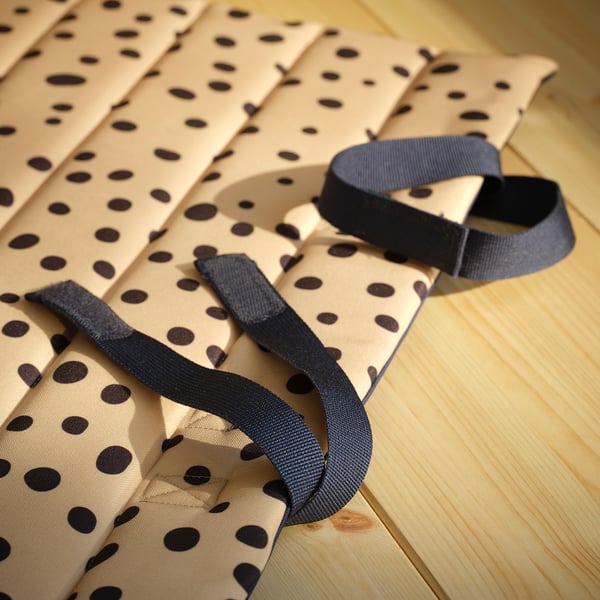 Folded spotted fabric mat with durable straps on wooden floor.