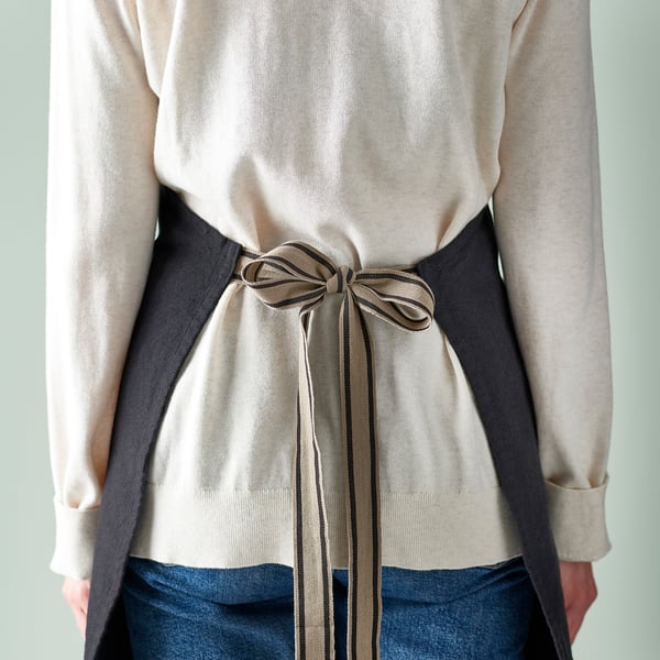 Apron with adjustable neck-band, loops, and pockets. Ideal for cooking, keeps clothes clean.