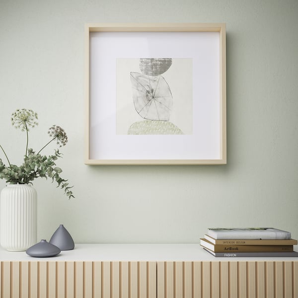 Framed abstract art on green wall, with shelf holding vase and books.