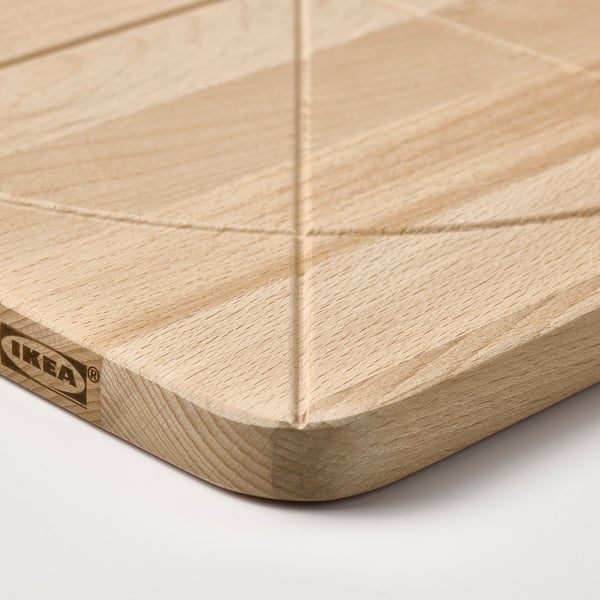 A high-quality wooden cutting board with a groove for catching juices, branded IKEA, showcasing its craftsmanship and durable solid beech material.