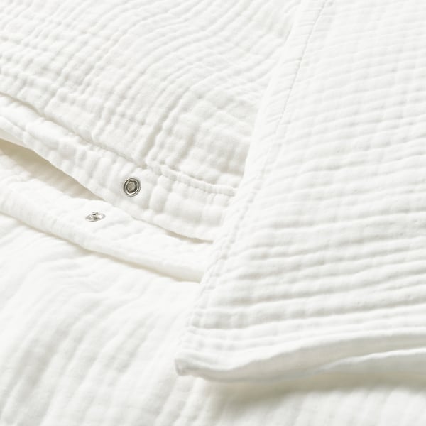 Close-up of white duvet cover set with snap closure, made of soft, organic cotton in a wavy muslin fabric.