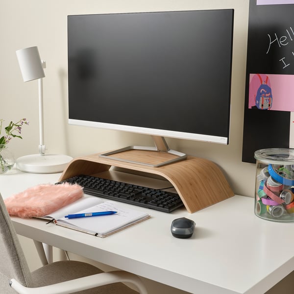 Home office with SIGFINN wooden monitor stand, keyboard, mouse, lamp on white desk.
