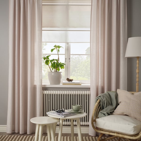 Pink sheer curtains with green chair beside large window.
