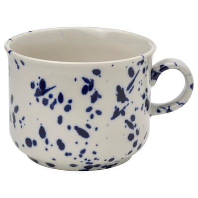 A white mug with blue splatter patterns, made of stoneware. It a sturdy handle and a speckled design, suitable for various settings.