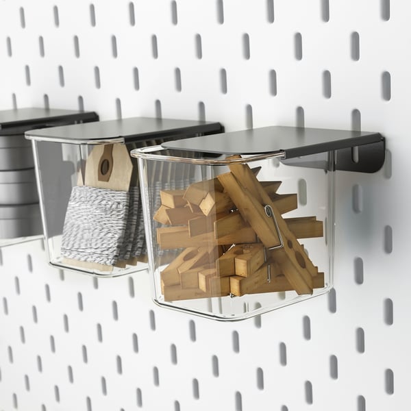Transparent SKÅDIS boxes hang on pegboard, storing wooden blocks and twine, keeping craft supplies organised.