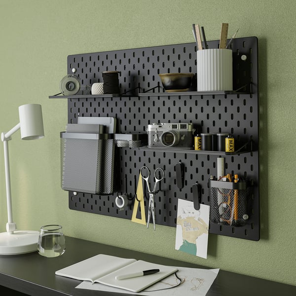 Wall-mounted SKÅDIS pegboard with shelves and accessories organises desk items like scissors, pens, and notebooks.