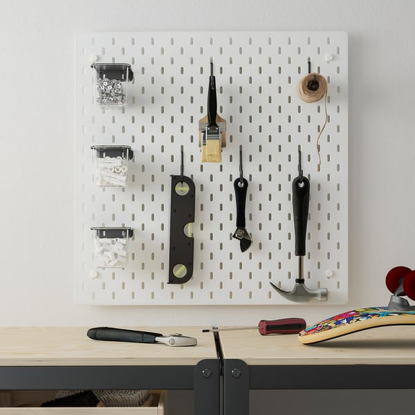 White SKÅDIS pegboard with tools and containers on wall.