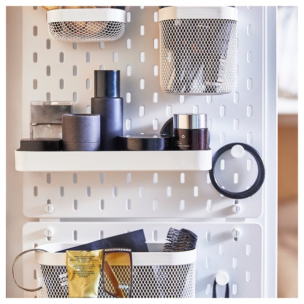 SKÅDIS white pegboard with mesh baskets, containers, and beauty products organised on shelves.