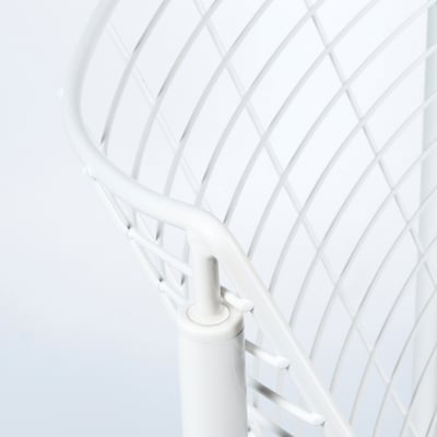 A close-up of a white metal chairs backrest, showcasing its intricate, curving lattice pattern and sturdy joints.
