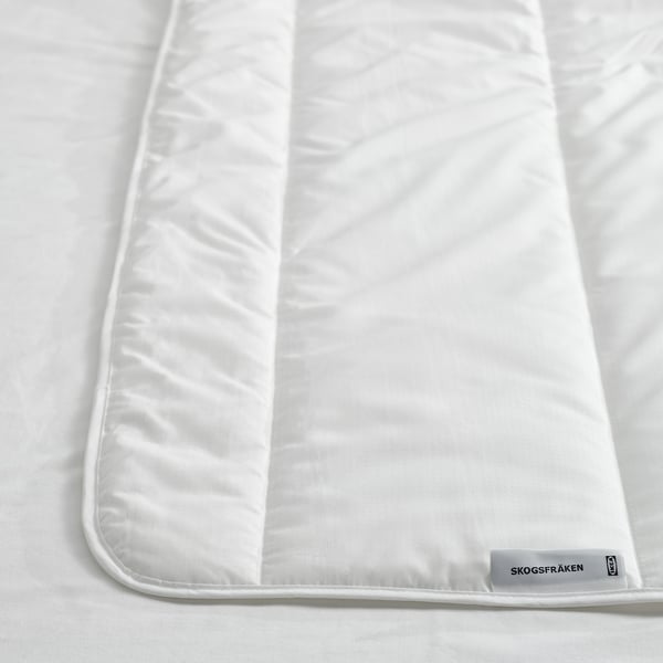 Crisp white duvet on bed, neatly folded; soft, fluffy texture, recycled materials.