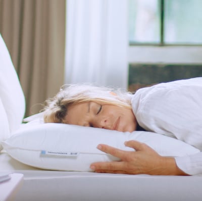 Person sleeping on white SKOGSFRÄKEN pillow. Pillow has soft polyester filling.
