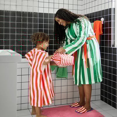 Person and child in matching striped bathrobes, bathroom.