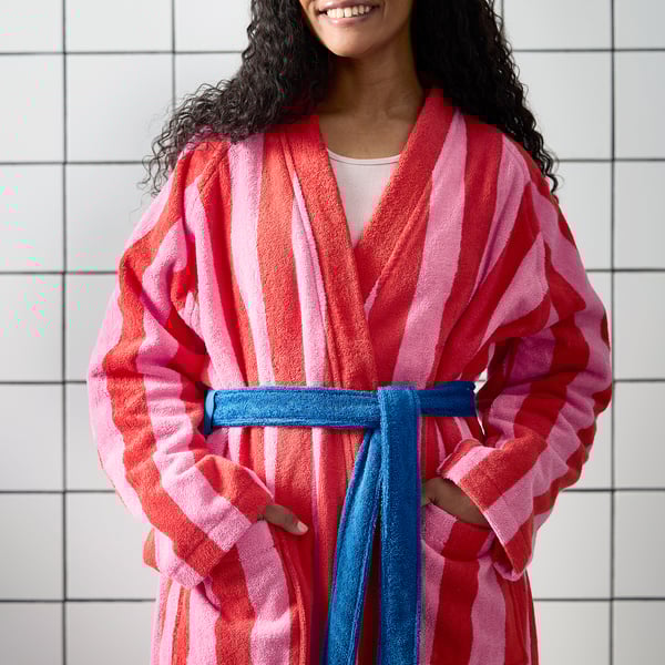 Person wearing colourful striped robe with blue belt, has pockets on sides, and adjustable belt loop.