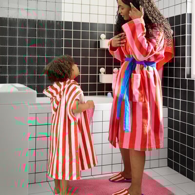 Two in striped robes in tiled bathroom.