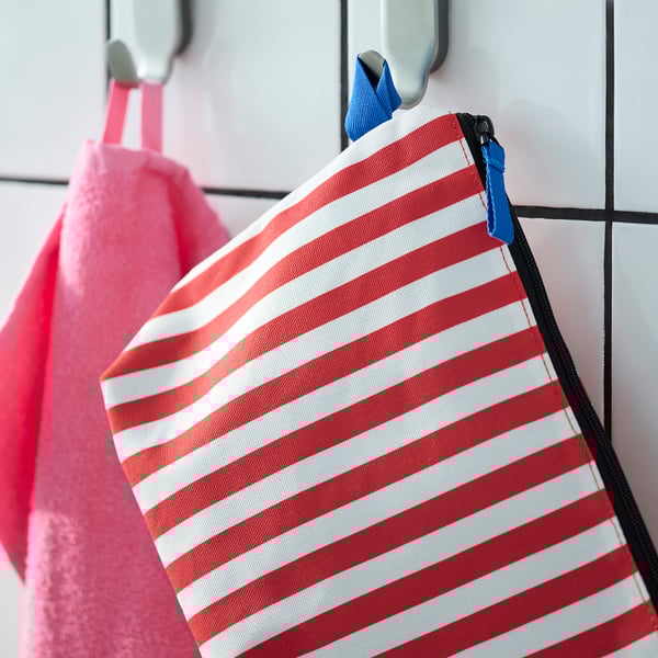 A striped toiletry bag hung on a hook, displaying its multiple compartments for organisation.