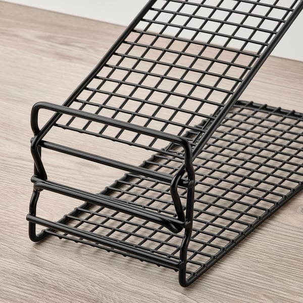 Black wire shoe rack, adjustable for space-saving storage, placed on wooden floor.