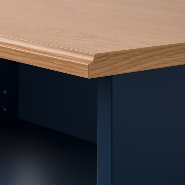 Close-up of SKRUVBY tv benchs edge, showing oak-like finish and sturdy profile on deep blue unit.